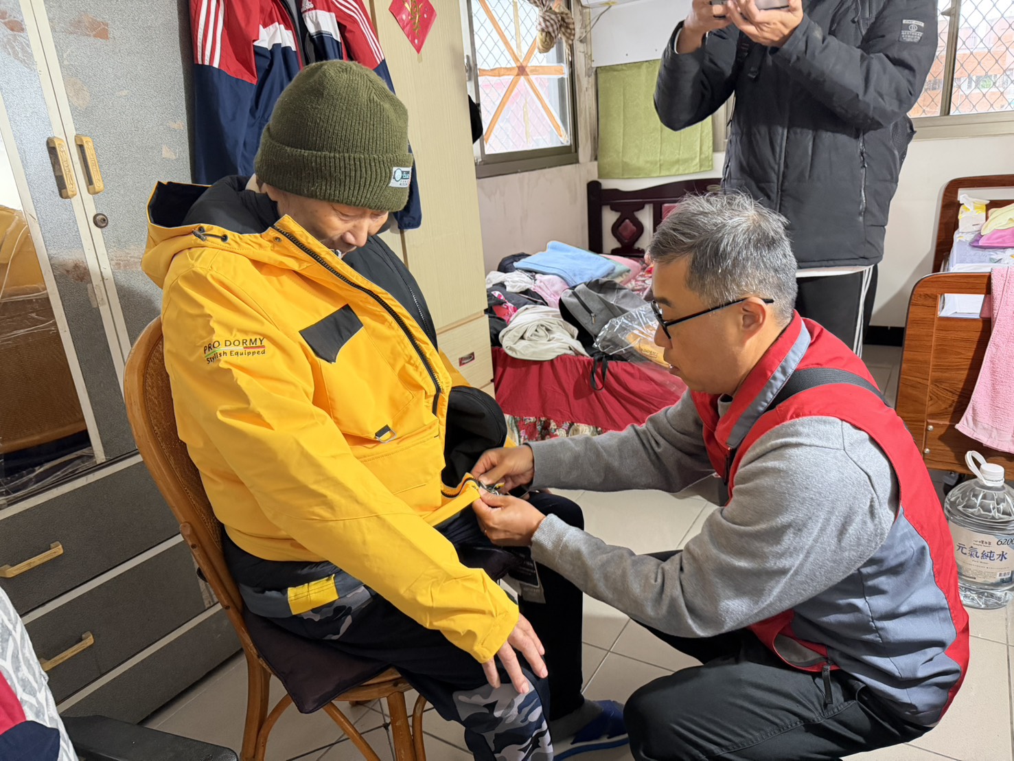 《圖說》李毓錫副處長貼心協助毛伯伯試穿保暖外套，並仔細調整尺寸。〈新北榮服處提供〉