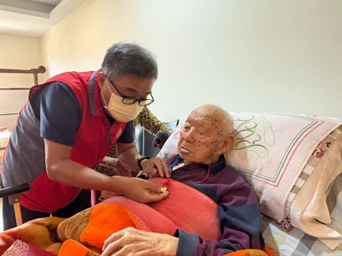 《圖說》李毓錫（左）貼心協助百歲榮民夏爺爺佩戴輔導會金飾壽桃。〈新北榮服處提供〉