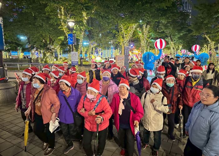 《圖說》新埔鎮輩戴著紅色的耶誕帽，隊伍由志工帶領，蜿蜒有如紅龍，在縣民大道引起矚目，也與馬戲團大象與氣球相映成趣。〈觀光局提供〉