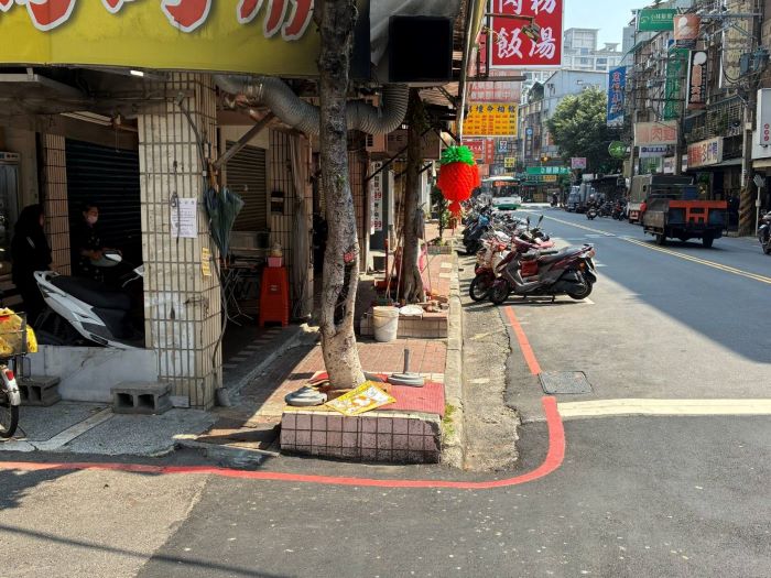 《圖說》蘆洲區民族路人行道鋪面破損、路樹及私設坡道阻礙通行，養工處移除拓寬後，人行道變得平整寬敞--施工前現場。〈工務局提供〉