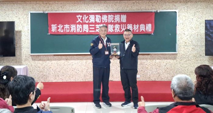 《圖說》新北市政府消防局張易鴻主任秘書代表消防局回贈三芝文化彌勒佛院消防公仔。〈消防局提供〉