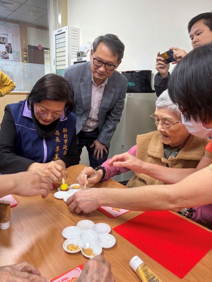 《圖說》李美珍局長和長輩一起製作春聯，中為廣恩老人養護中心董事長林偉峰。〈社會局提供〉
